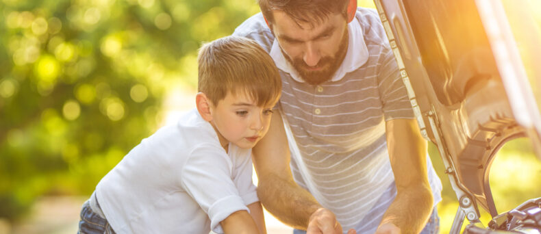 Man and child check the fluids of a car
