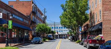 Street view of historic downtown Canton, Georgia with brick storefronts, local shops, and parked cars along a walkable main road.