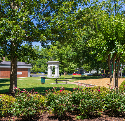 Green park setting with trees, flowers, and a playground at Brown Park in historic downtown Canton, Georgia.
