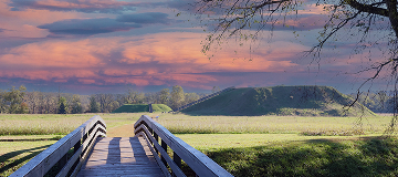 A wooden boardwalk leading across grassy fields toward the Etowah Indian Mounds, highlighting the historic Native American site in Cartersville, Georgia.
