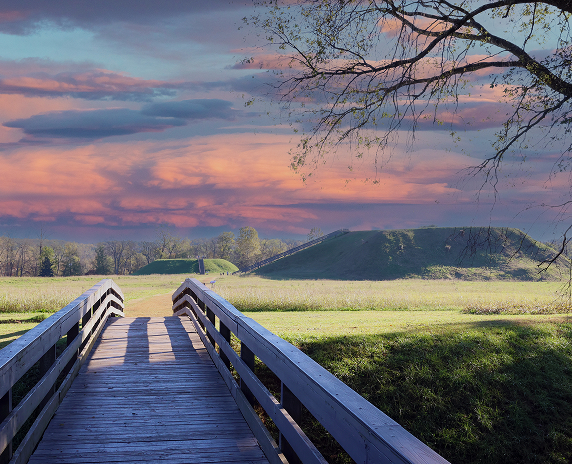 A wooden boardwalk leading across grassy fields toward the Etowah Indian Mounds, highlighting the historic Native American site in Cartersville, Georgia.