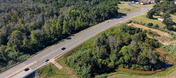 An aerial view of a highway cutting through wooded and rural landscapes, illustrating transportation and surrounding countryside near Perry, Georgia.