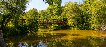 Footbridge crossing the Little River surrounded by trees at Olde Rope Mill Park in Woodstock, Georgia