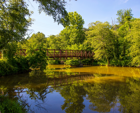 Footbridge crossing the Little River surrounded by trees at Olde Rope Mill Park in Woodstock, Georgia